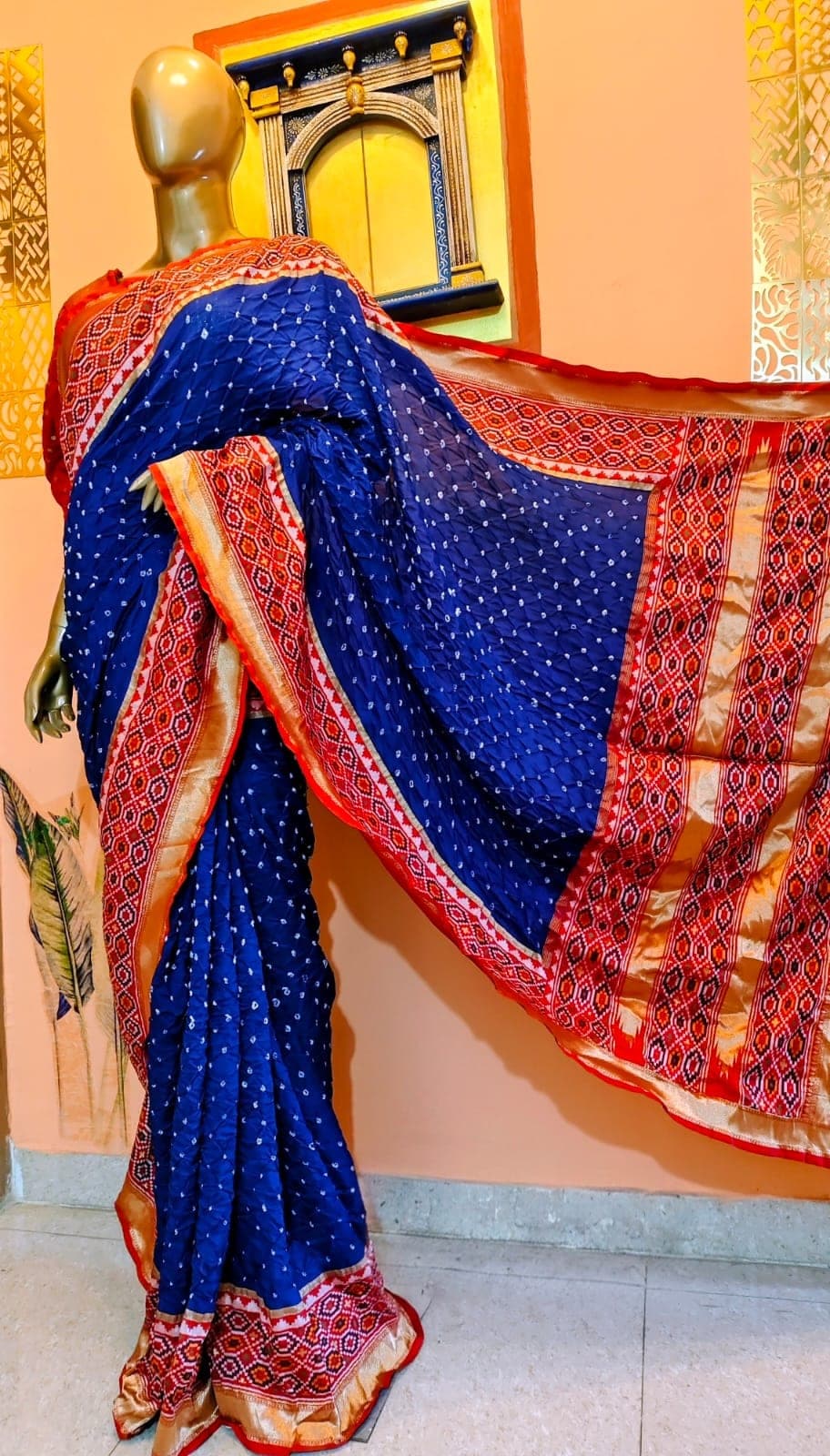 Indigo saree with a red-orange figured border, on a stand